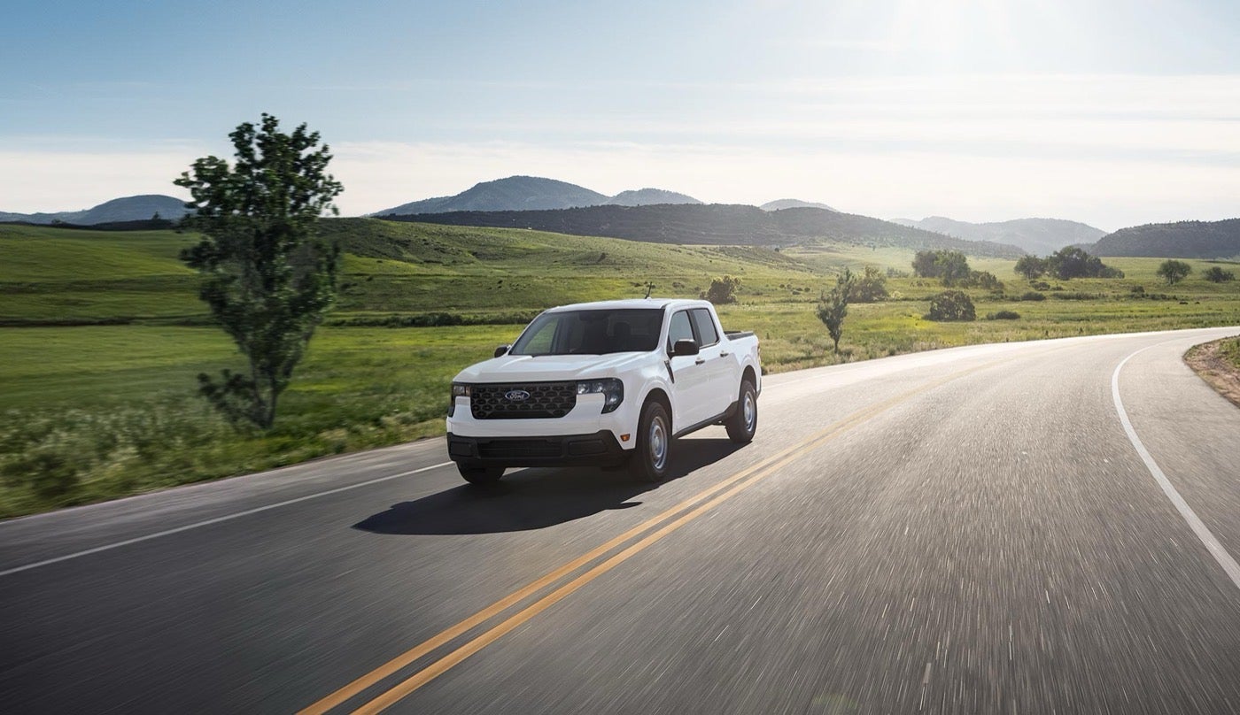 White Ford Maverick pickup driving on a country highway