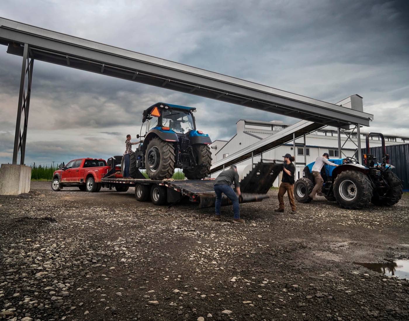 Red Ford Super Duty hitched to a trailer as workers load a tractor